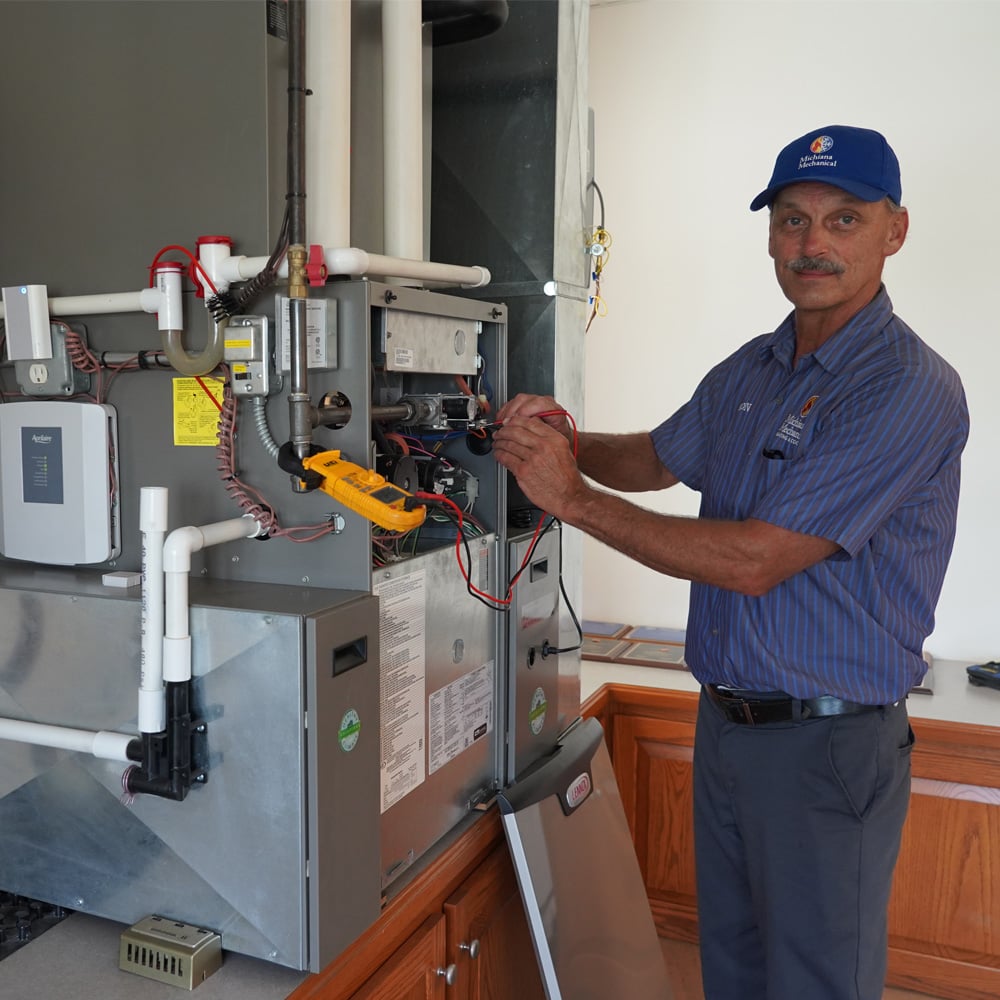 Michiana Mechanical technician using multimeter to test indoor HVAC equipment during maintenance