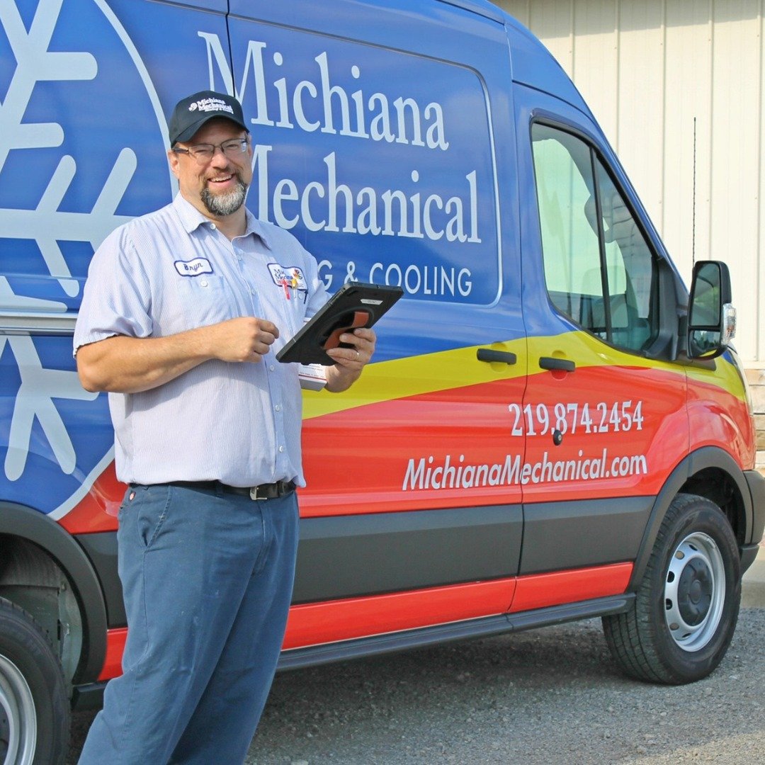 486777510_1152178796922005_4304308311075971766_n Michiana Mechanical technician smiling with tablet in front of branded service van