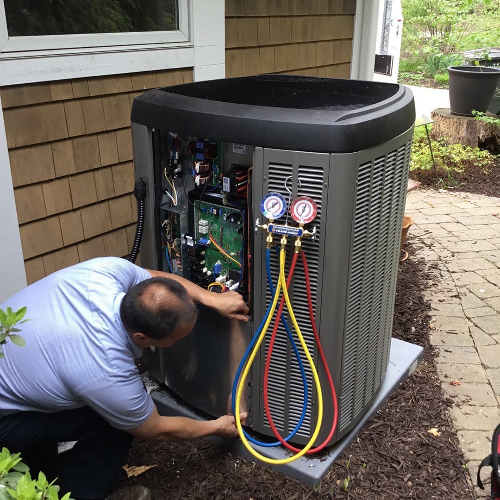 HVAC technician diagnosing outdoor air conditioning system with pressure gauges