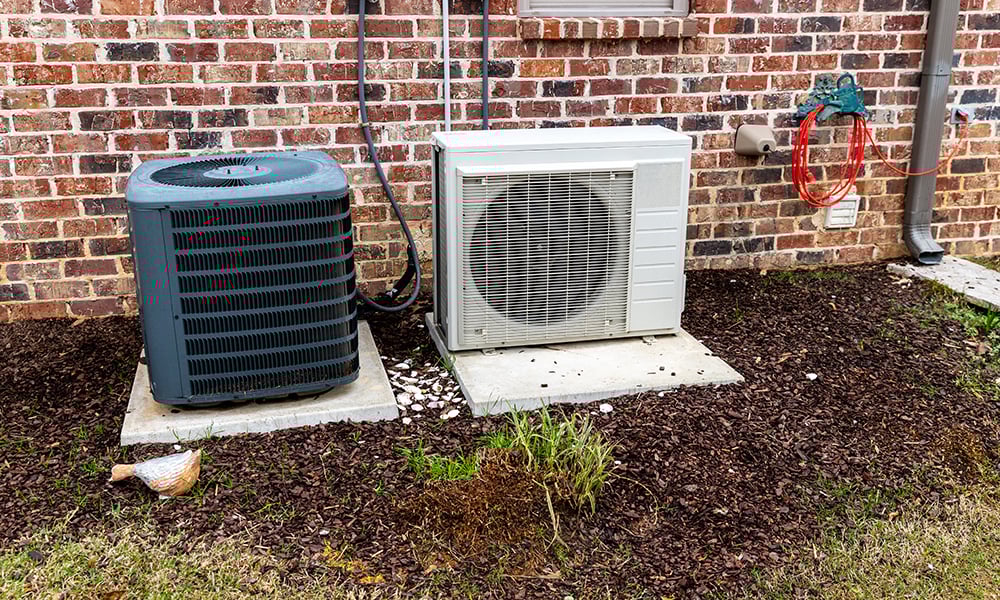 Outdoor air conditioner and heat pump system installed beside a brick house