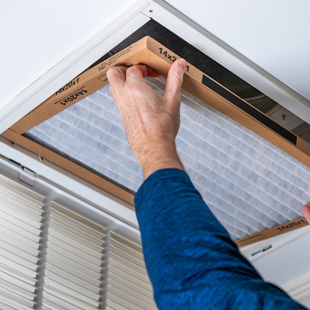 Person changing a 14x20x1 HVAC air filter in ceiling-mounted vent