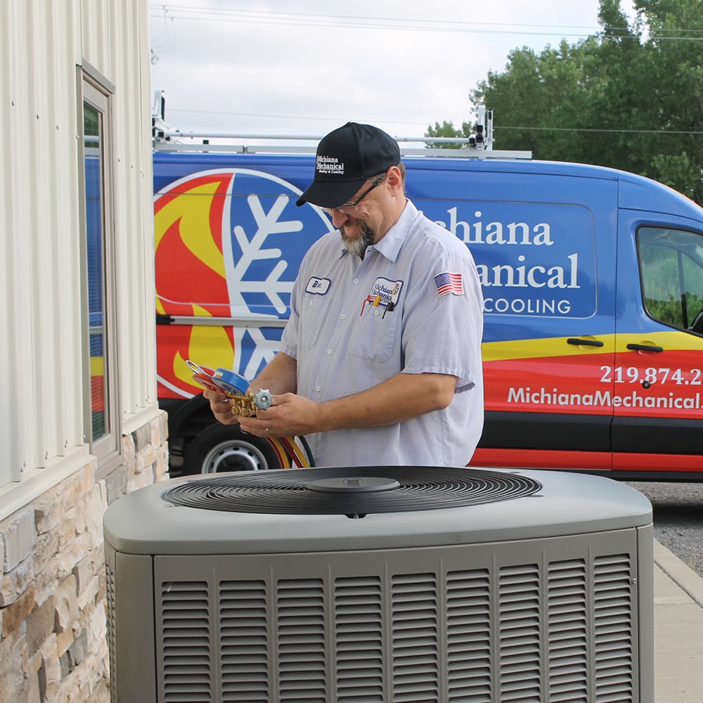 Technician checking refrigerant levels on an outdoor AC unit beside a building
