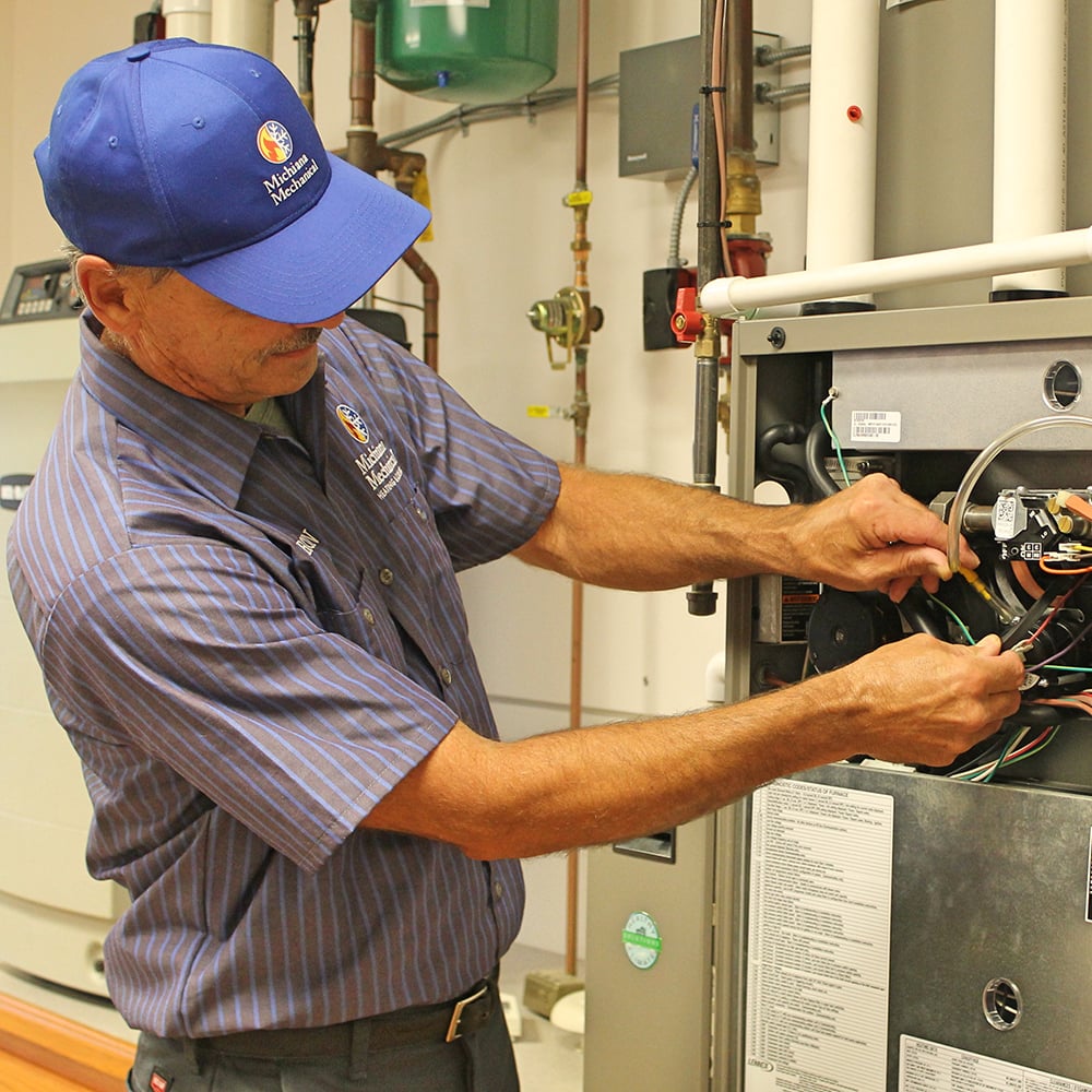 HVAC technician repairing wiring inside a heating unit