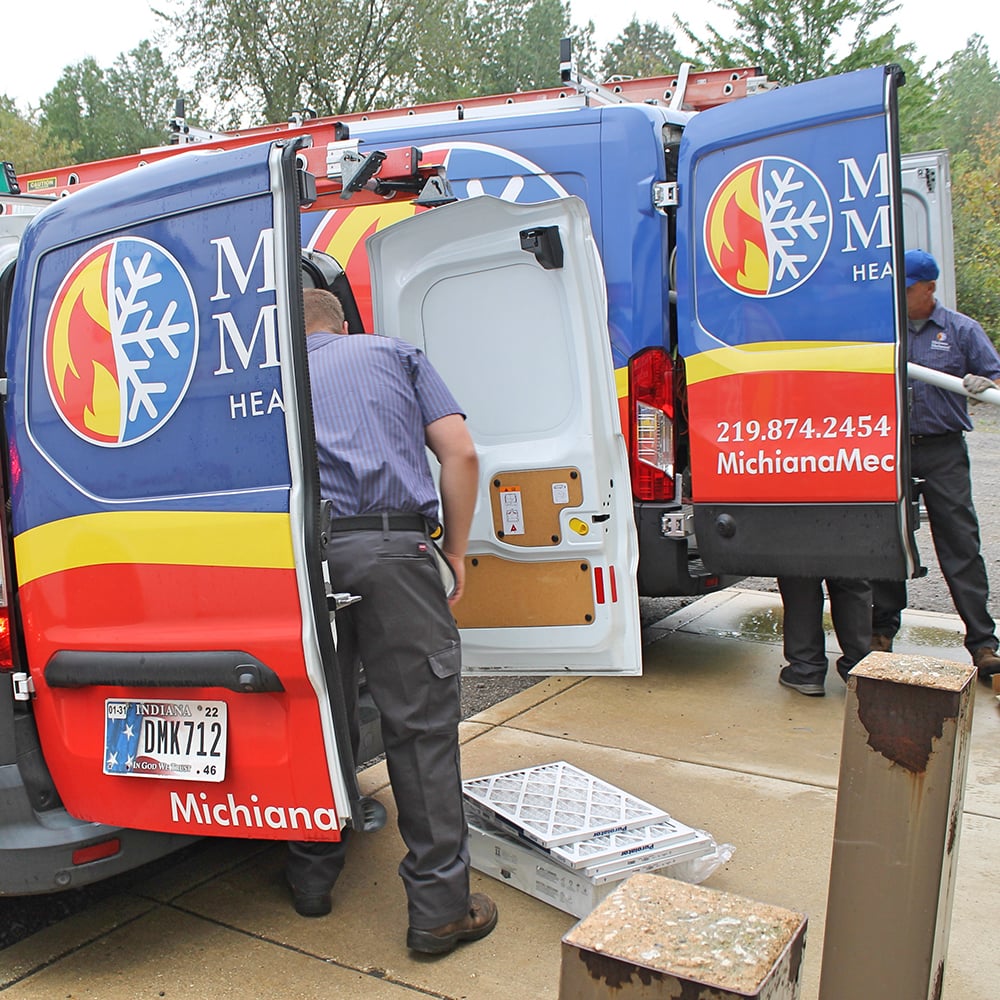 Technician unloading air filters from back of Michiana Mechanical van