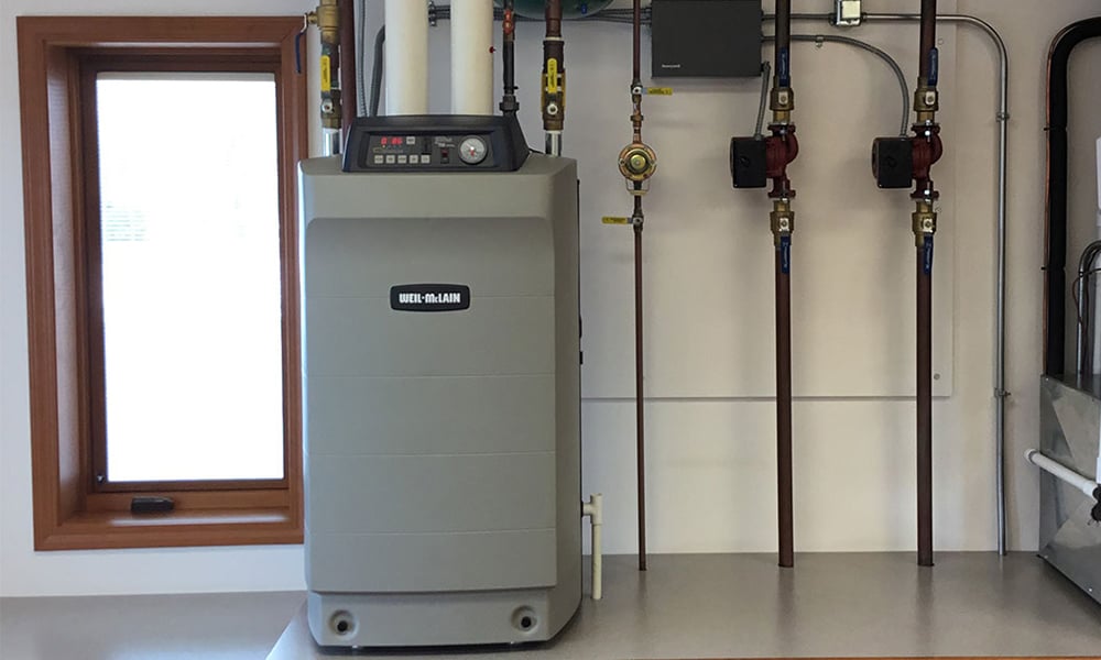 Weil-McLain boiler system installed beside a window in a utility room